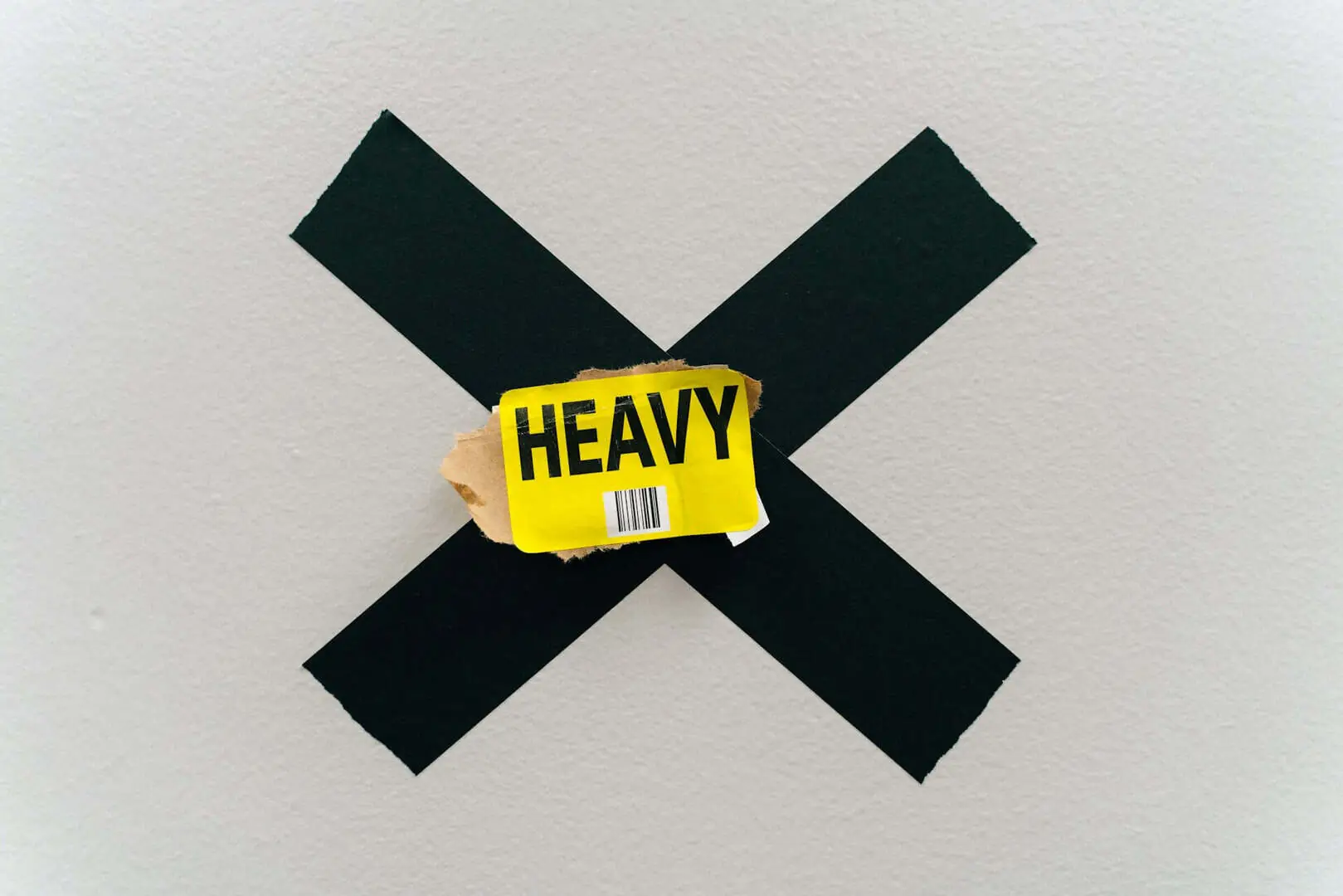 A yellow ‘HEAVY’ warning label positioned centrally over a large black ‘X’ mark