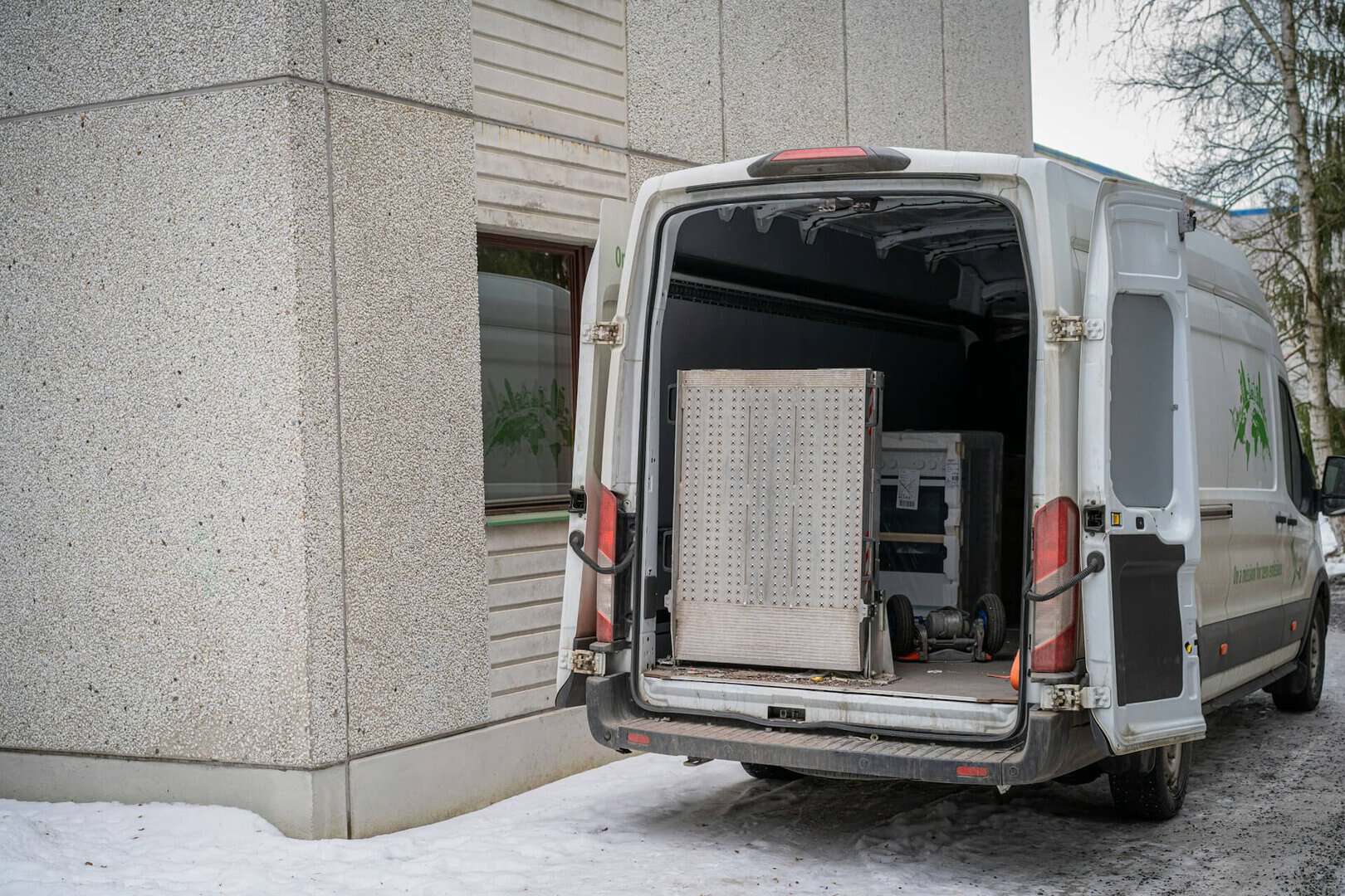 Rear view of an open white removal van prepared for loading heavy items during a move