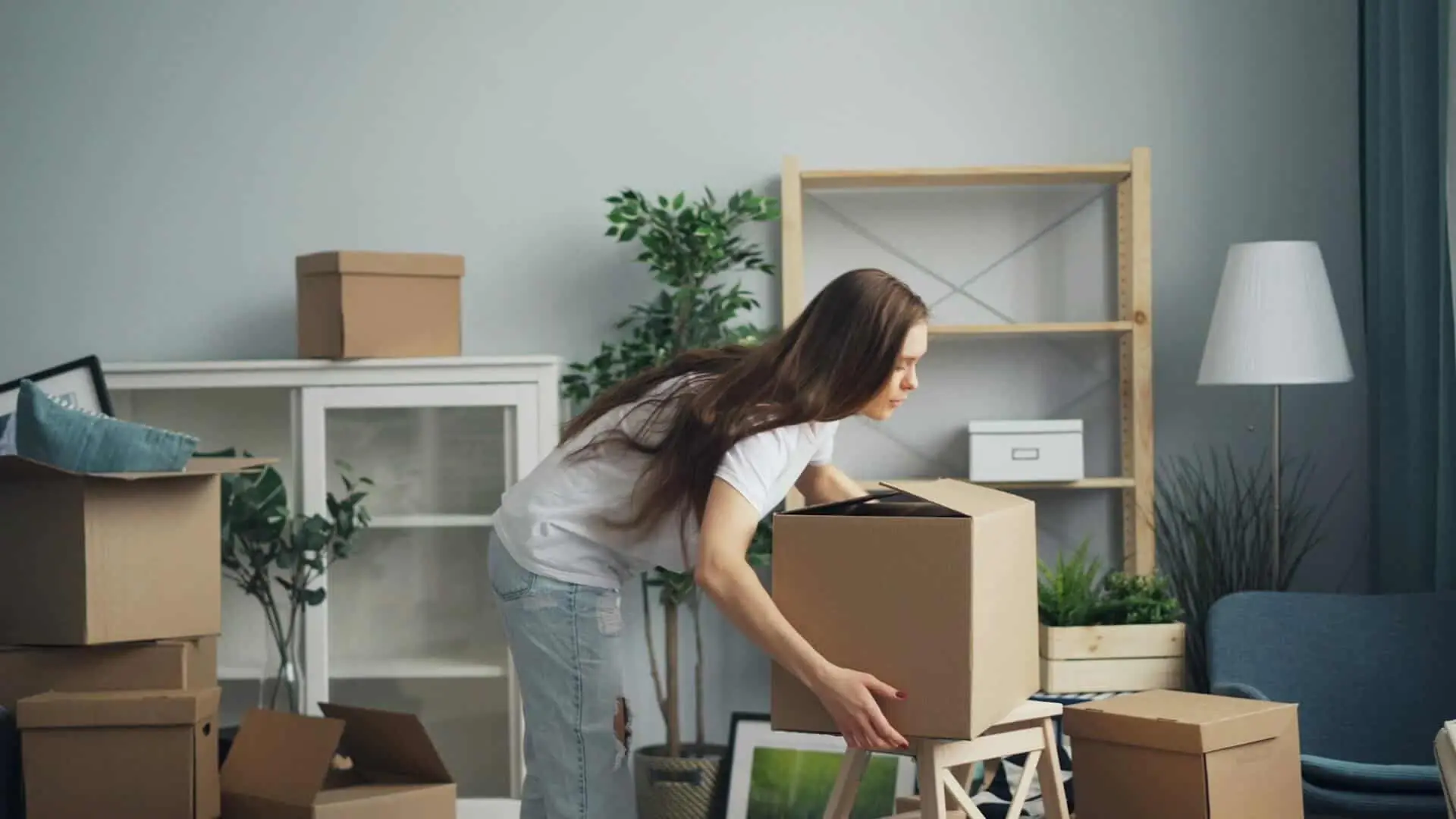 Woman packing belongings into a moving box during a home relocation