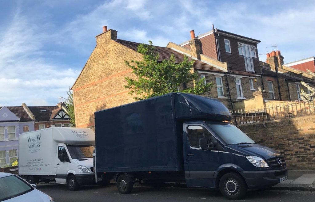 Two removal vans parked on a residential street in front of terraced houses