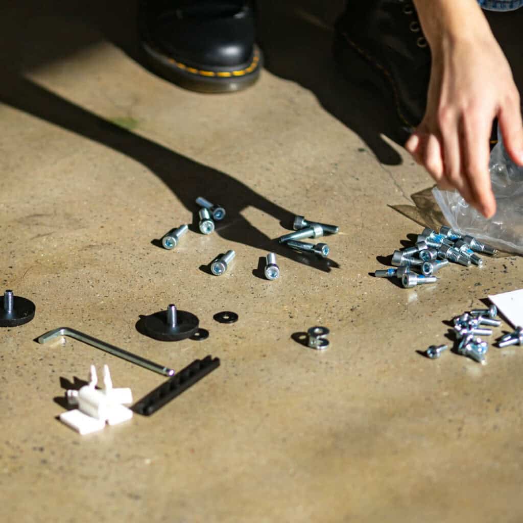 Furniture fittings — bolts, screws, an Allen key, and fixtures — laid out on the floor during a professional furniture dismantling and assembly service